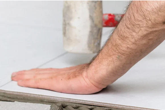 Hand verlegt Fliese mit Gummihammer